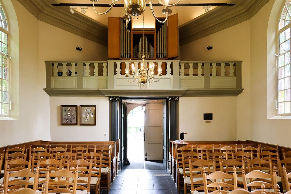 Interieur van het Van Goghkerkje in Nuenen, met orgel en houten banken